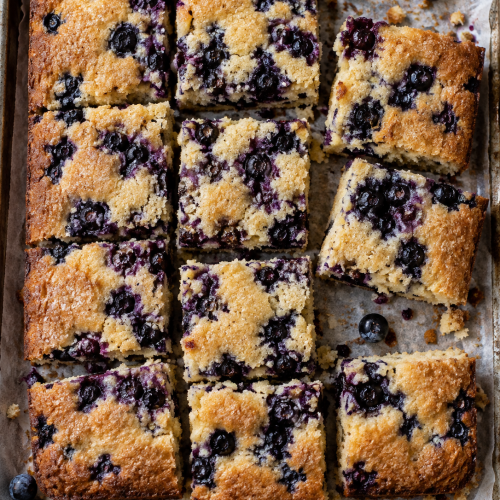 Stücke Heidelbeer-Blechkuchen direkt auf Backpapier von oben fotografiert